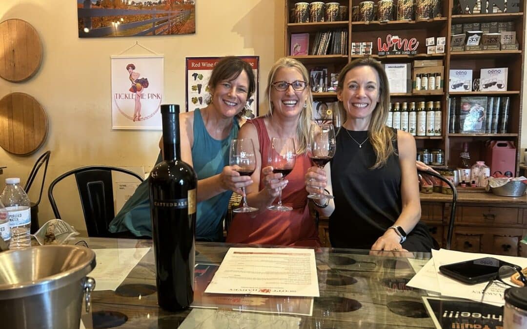 woman sitting at table holding up wine